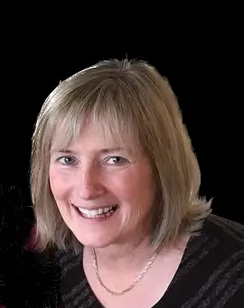 Smiling woman with blonde hair wearing a dark top against a black background.